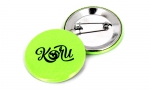 Badge rond 45mm sur fond fluo vert.
Visuel : 'Logo Koru.'