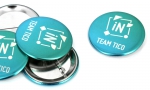 Panachage de badges ronds 56mm sur fond métal.
Visuel : 'Logo Intuitis, Team Tico.'